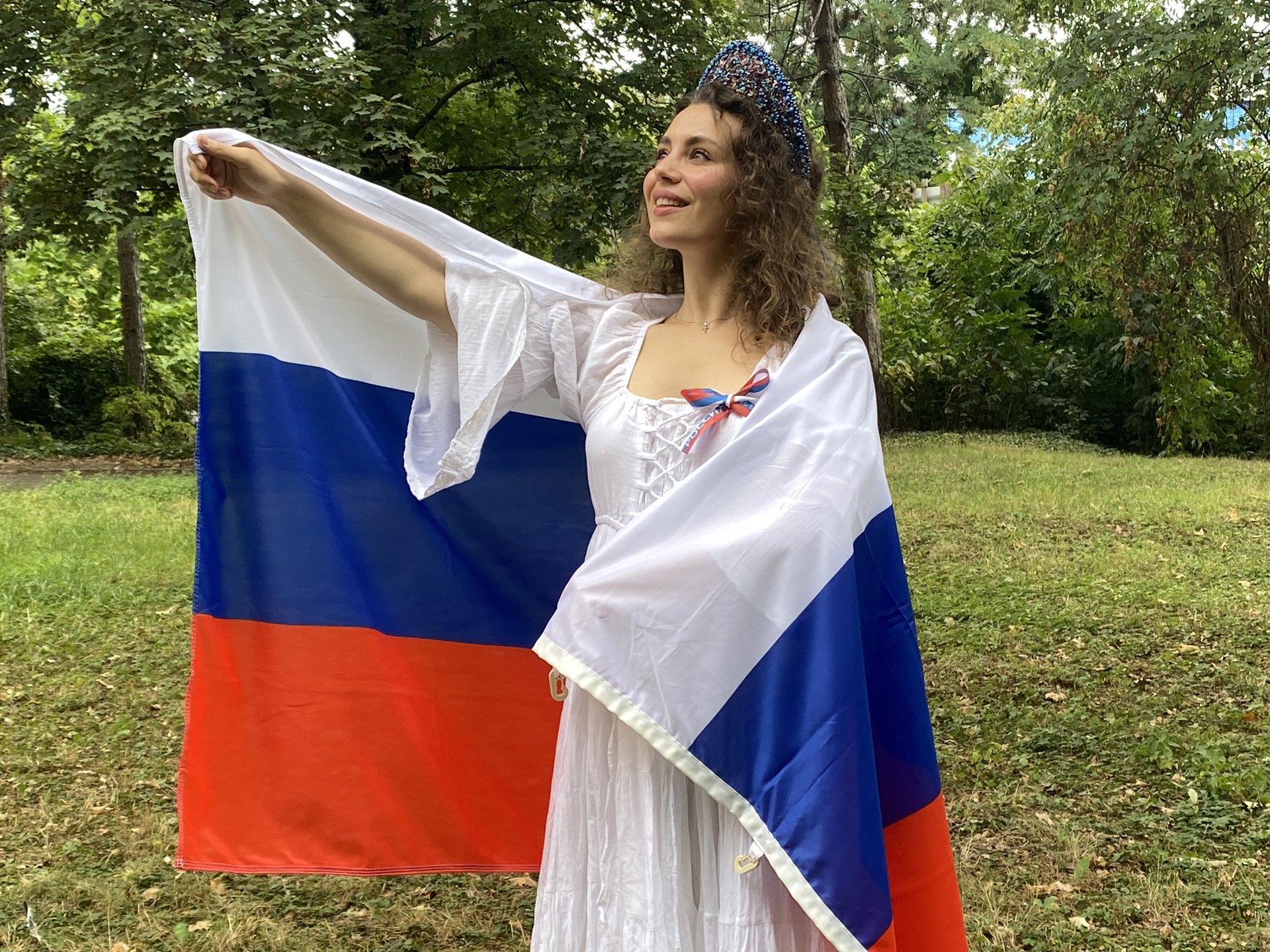 Девушка в белом платье и кокошнике с российским флагом